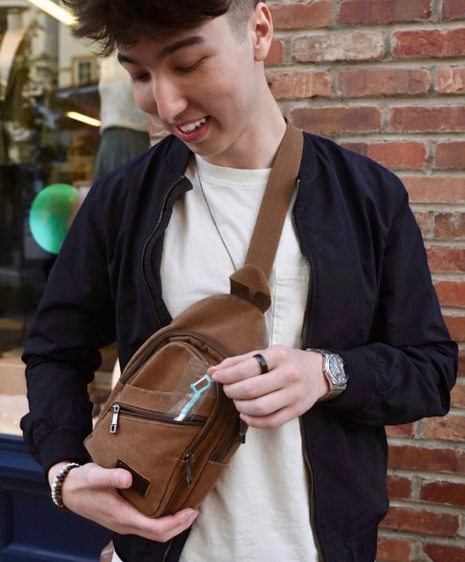 Man putting a Brushee toothbrush into a backpack