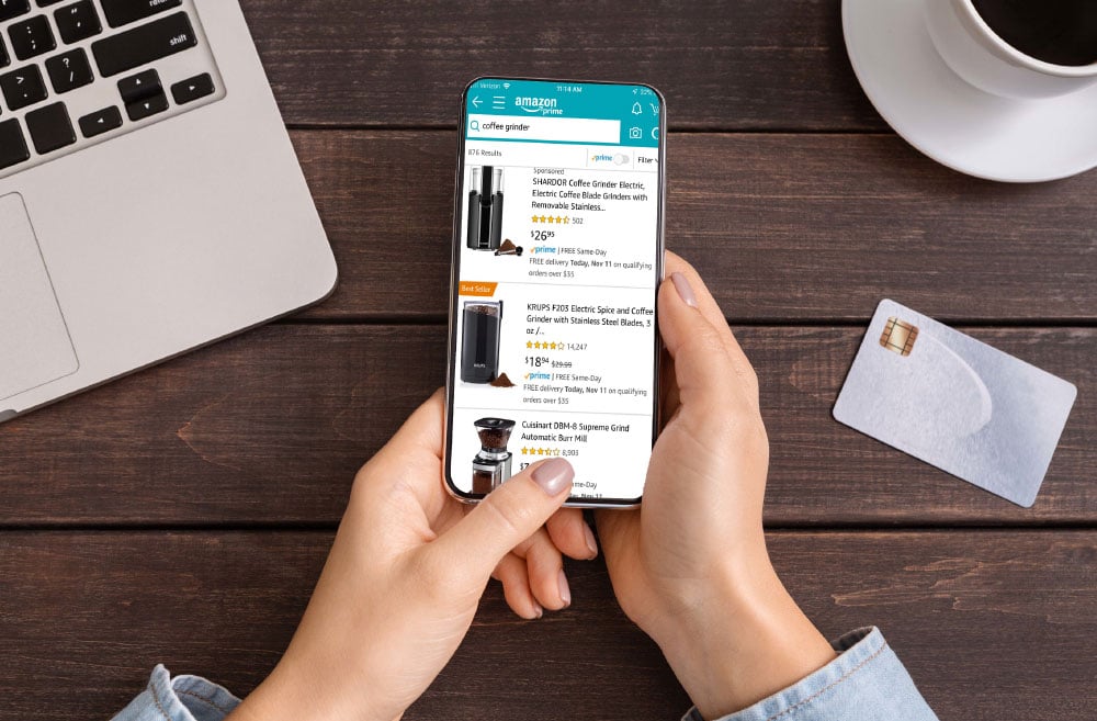 Two female hands holding a smartphone that is browsing Amazon.com for coffee grinders